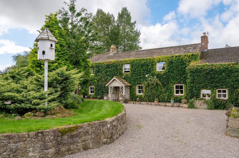 Sun Hill Farmhouse exterior with ivy-covered stone walls, gravel driveway and landscaped garden.