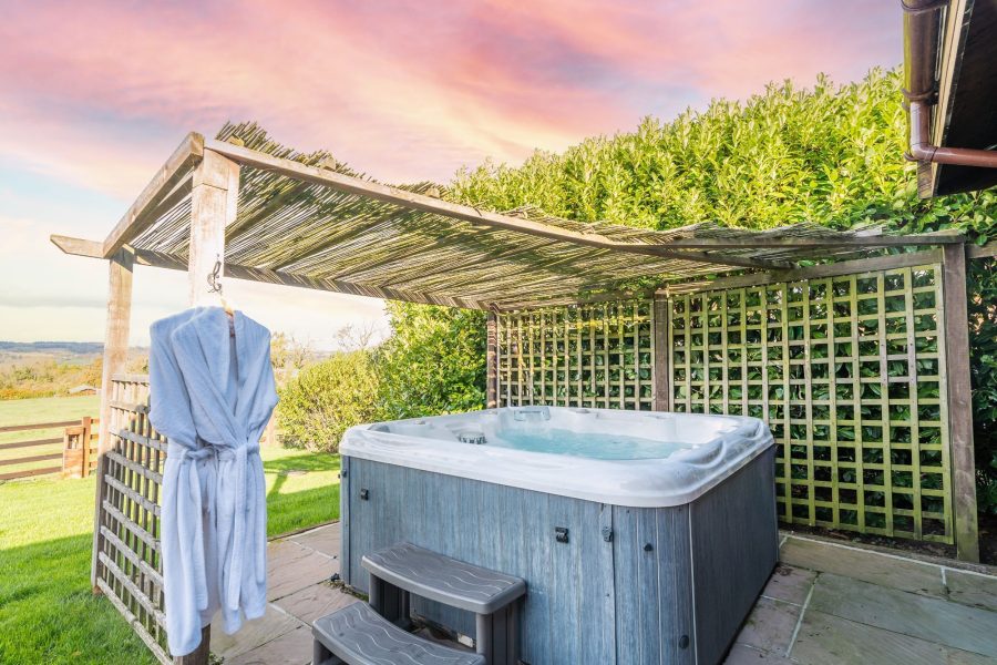 Outdoor hot tub with countryside views at Ninetta lodge.