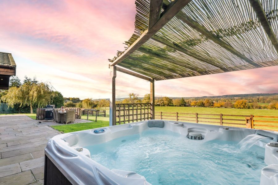 Hot tub with countryside views and outdoor dining area at Ninetta lodge.