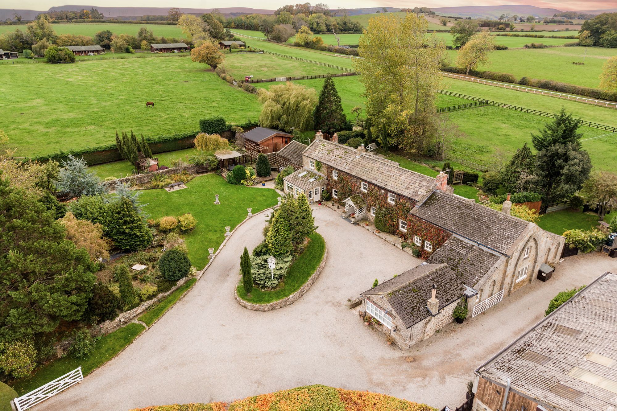 Aerial view of Sun Hill Farm with ivy-covered stone walls, gravel driveway and landscaped garden.