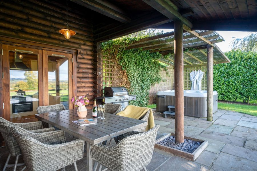 Luxury log cabin patio with outdoor dining, BBQ and covered hot tub at Woodlands