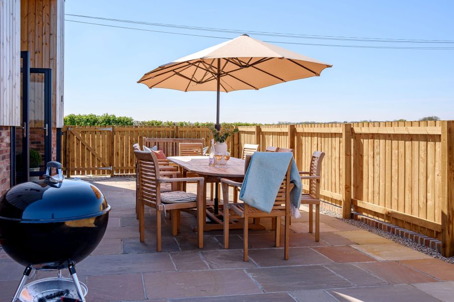 Outdoor dining with BBQ at The Big Green Barn, a self-catering holiday cottage, set within a fenced private area.