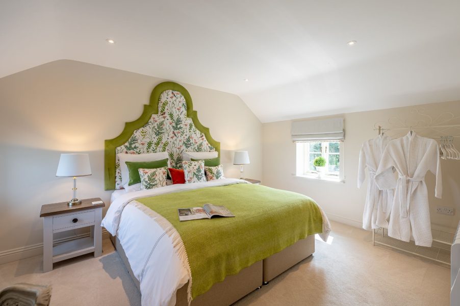 Luxury double bedroom with decorative headboard and soft green accents at Feathered Nest holiday cottage