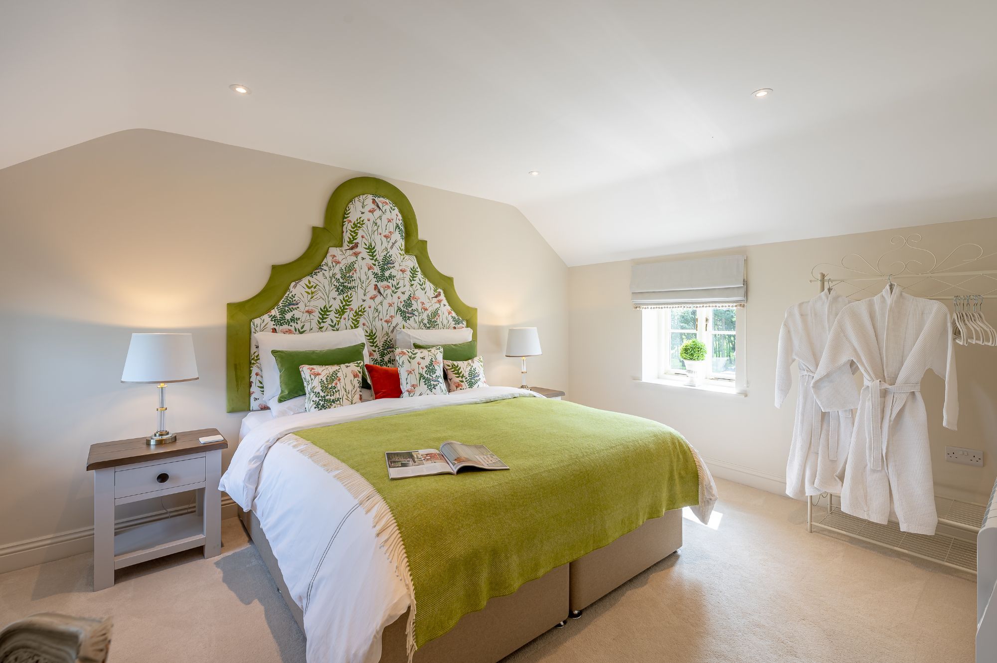 Luxury double bedroom with decorative headboard and soft green accents at Feathered Nest holiday cottage
